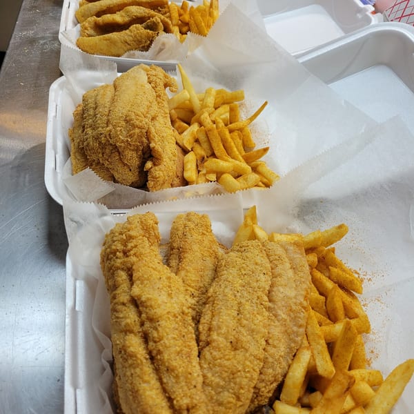 Three Hooks Fish & Chicken Plus takeout containers filled with crispy fried fish and seasoned fries.