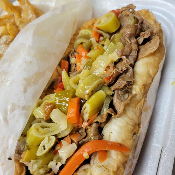 Close-up of a Hooks Fish & Chicken Plus Italian beef sandwich with giardiniera and fries.