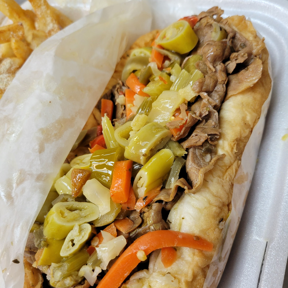 Close-up of a Hooks Fish & Chicken Plus Italian beef sandwich with giardiniera and fries.